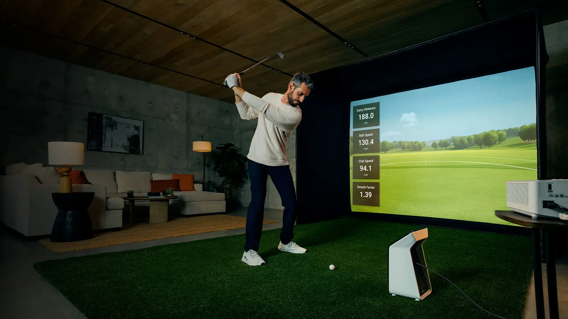 Golfer swinging in an indoor simulator setup with the Garmin R50 and projector screen