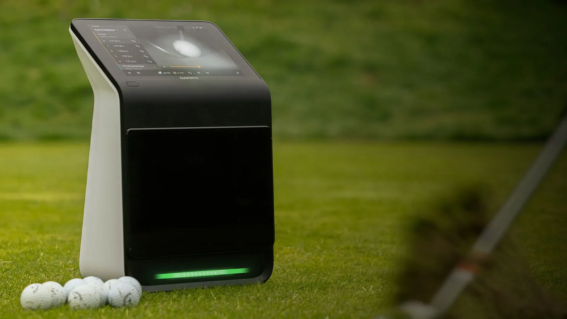 Angled view of the Garmin R50 on grass with golf balls in the foreground